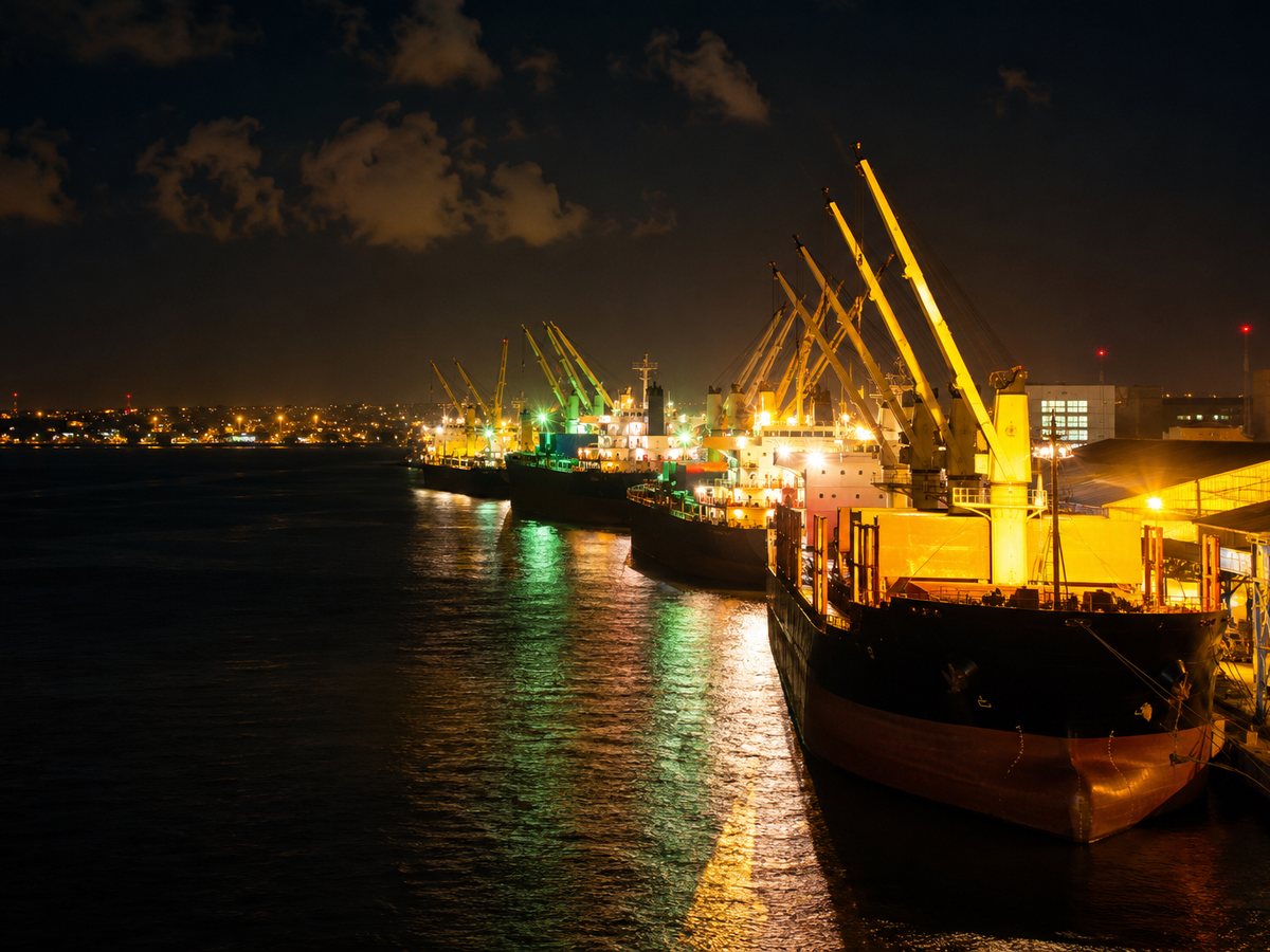 Navios e gruas em operacao noturna num porto comercial